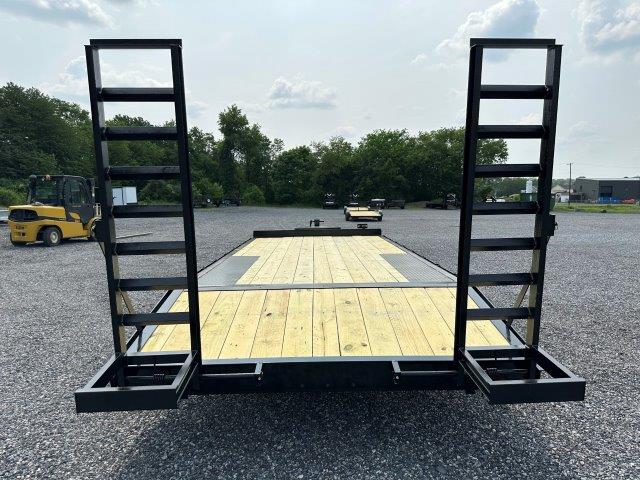 a trailer with a wooden deck and stairs is parked in a gravel lot