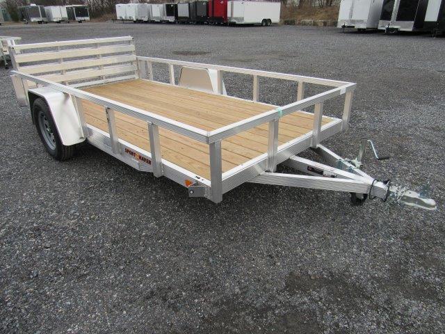 a trailer with a wooden deck is parked in a gravel lot