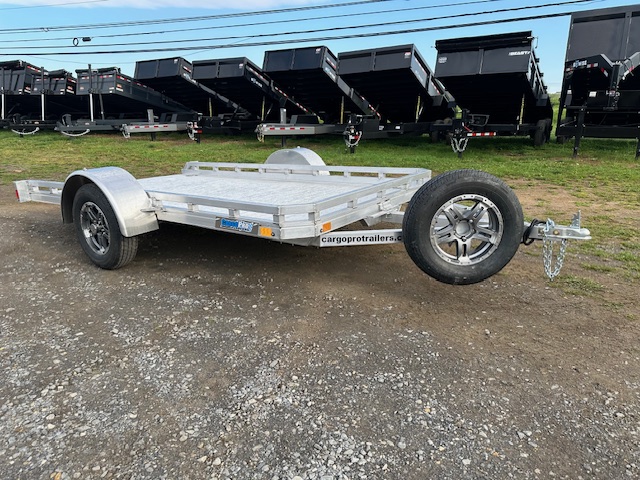 a silver trailer parked in front of dump trailers