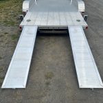 a trailer with ramps attached to it is parked on the side of the road .