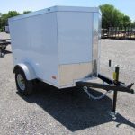 a white trailer is parked in a gravel lot .