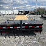 a flatbed trailer is parked in a gravel lot .