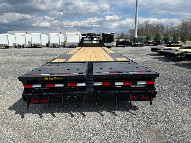 a flatbed trailer is parked in a gravel lot .