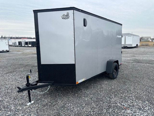 a silver trailer with the word cargo wagon on the side is parked in a gravel lot