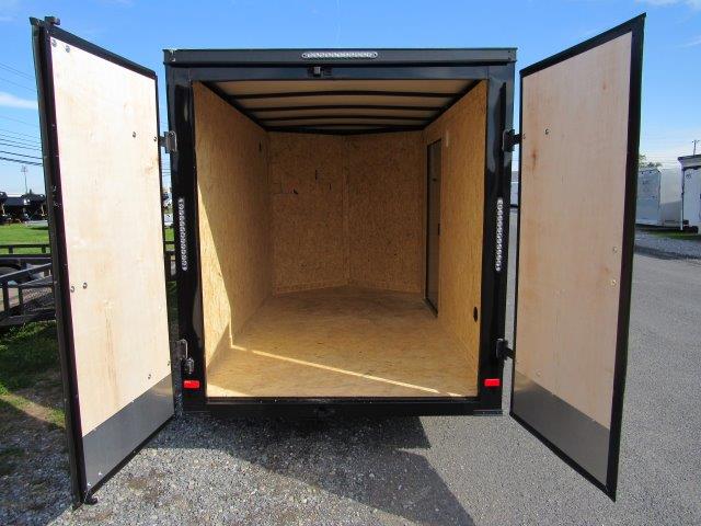 the back of an empty trailer with its doors open .