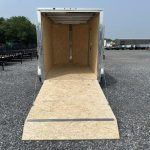 a trailer with the door open is parked in a gravel lot .