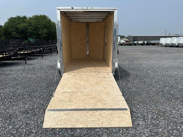 a trailer with the door open is parked in a gravel lot .