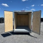 an empty trailer with its doors open is parked in a parking lot .