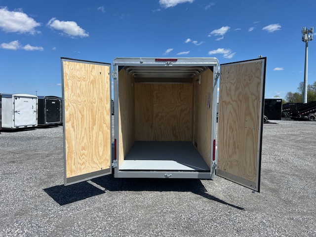 an empty trailer with its doors open is parked in a parking lot .