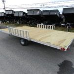 a trailer with a wooden deck is parked on the side of the road .