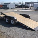 a flatbed trailer is parked in a gravel lot