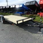 a trailer is parked on the side of the road next to a dumpster .