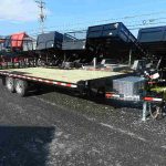 a flatbed trailer is parked on the side of the road .