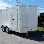 a white trailer with a ladder attached to the side is parked on the side of the road