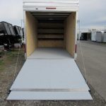 a white trailer with the door open is parked on the side of the road .