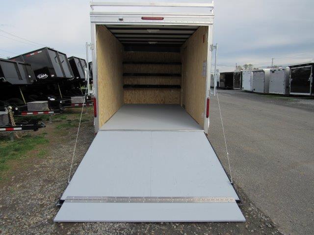 a white trailer with the door open is parked on the side of the road .