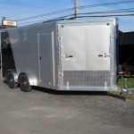 a silver trailer is parked on the side of a road next to a truck