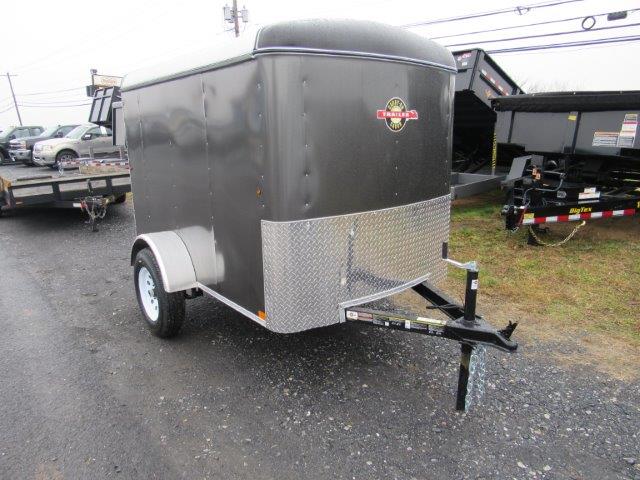 a black trailer is parked on the side of the road next to a dump trailers .