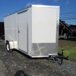 a white trailer is parked on the side of the road .