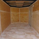 an empty trailer with wooden walls and a door .