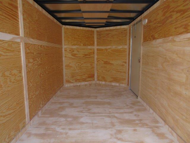 an empty trailer with wooden walls and a door .