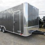 a black trailer is parked in a gravel lot