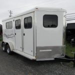 a white horse trailer is parked on the side of the road