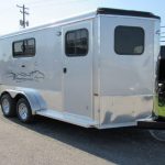 a white horse trailer is parked on the side of the road .