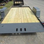 a trailer with a wooden deck is parked on the side of the road .