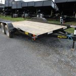 a trailer with a wooden deck is parked on the side of the road