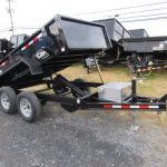 a dump trailer is sitting on top of a dirt field .