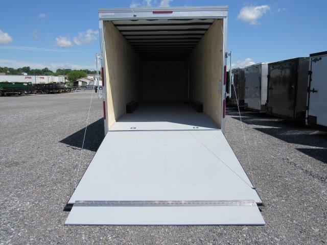 a trailer with the door open is parked in a gravel lot .