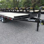 a row of trailers are parked in a gravel lot .