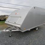 a silver trailer is parked in a gravel lot .