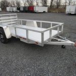 a small aluminum trailer is parked in a gravel lot