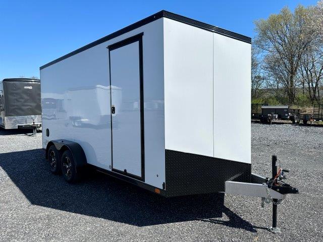 a white and black trailer is parked in a gravel lot