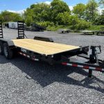 a flatbed trailer is parked in a gravel lot .