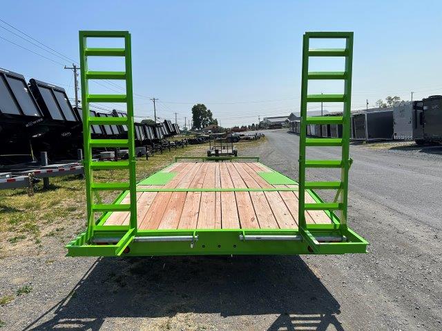 a green trailer with a wooden deck is parked on the side of the road .