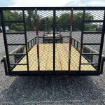 a trailer is parked in a gravel lot with a fence around it .