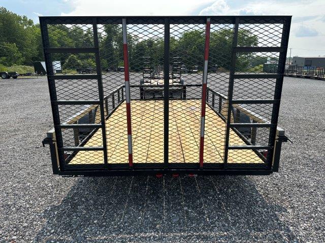 a trailer is parked in a gravel lot with a fence around it .