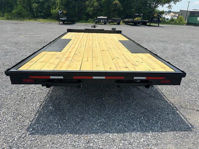 a trailer with a wooden deck is parked in a gravel lot .