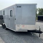 a gray and black trailer is parked in a gravel lot