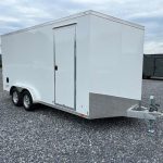 a white trailer is parked in a gravel lot .