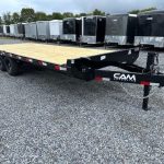 a flatbed trailer is parked in a gravel lot next to a row of trailers .