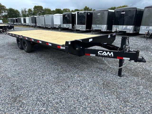 a flatbed trailer is parked in a gravel lot next to a row of trailers .