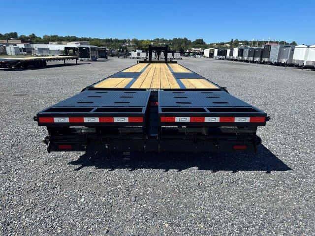 a trailer with a wooden deck is parked in a gravel lot