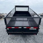 the back of a trailer with a mesh fence on it is parked in a gravel lot .