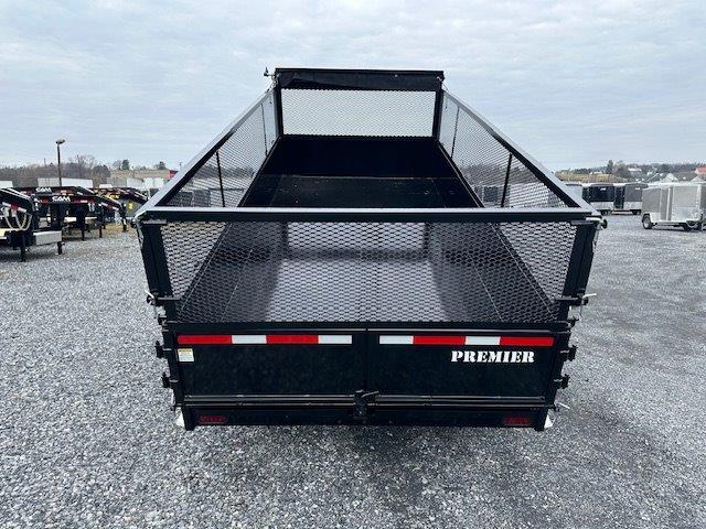 the back of a trailer with a mesh fence on it is parked in a gravel lot .