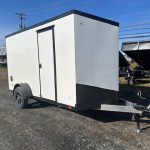 a white trailer with black trim is parked in a gravel lot