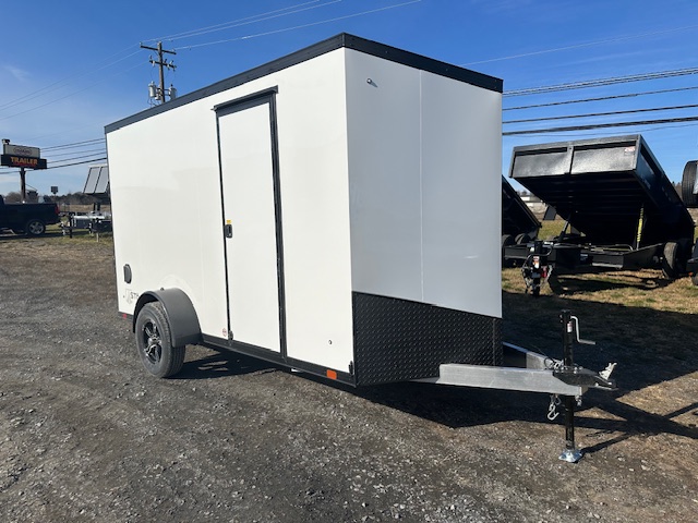 a white trailer with black trim is parked in a gravel lot